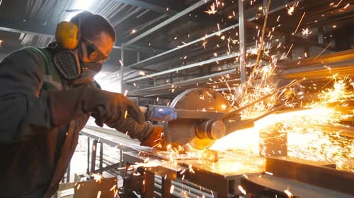 Handwerker beim Sägen von Metall mit Scheibenschleifer in Werkstatt