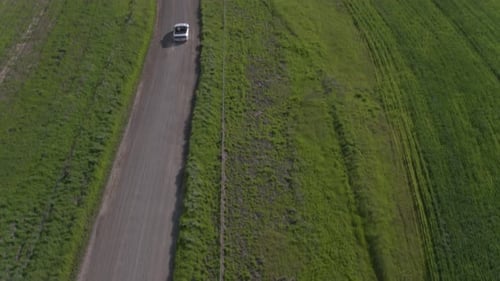 Car Driving On The Dirt Road Among Windmills