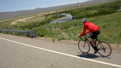 A man road biking on a scenic road.
