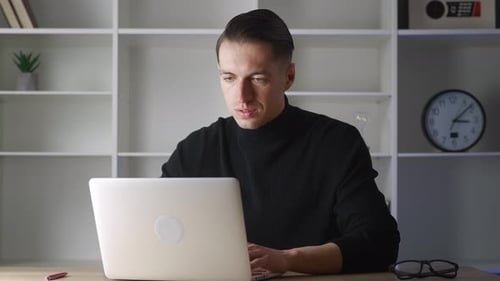 Man in black top working on laptop indoors