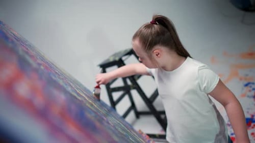 Young Girl Painting a Colorful Picture in Studio