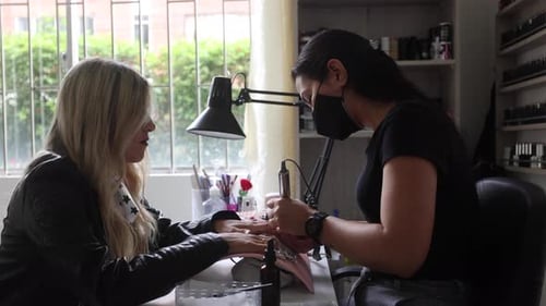 Anonymous master polishing nails of female customer with electric file