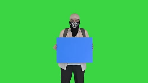 Jeune homme manifestant au visage couvert tenant un tableau blanc sur un écran vert Chroma Key