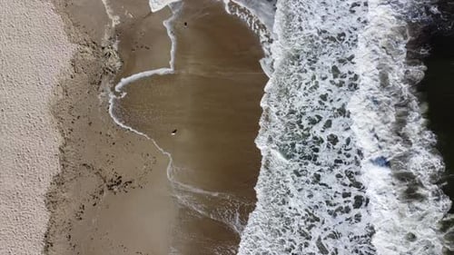 Drohnenflug über schöne Meereswellen am Sandstrand mit weißem Schaum