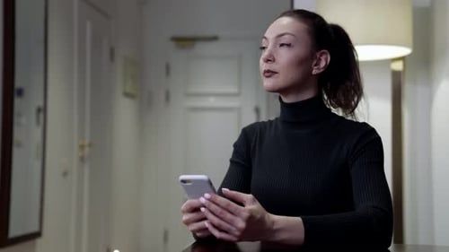 Adult Woman Is Thinking and Typing Message By Smartphone Sitting at Home