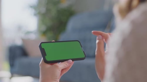 Woman Using Smartphone with Green Screen Indoors