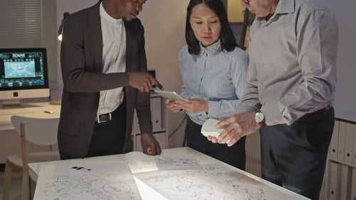 Team Collaborates Over Blueprint and Model in Office