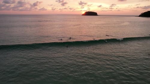 Surfers Riding Waves in Tropical Sunset from Above