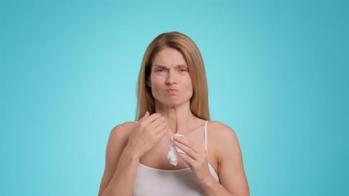 Woman with Blonde Hair Wipes Nose with Tissue