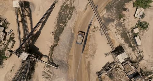 Quarry during work hours with Stone sorting conveyor belts and an open pit mine.