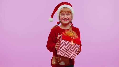 Excited Girl Receives Christmas Gift Wearing a Santa Hat