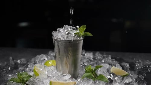 Water Pouring into Metal Shaker with Mint and Limes