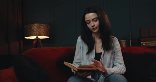 Woman Reading a Book on a Red Sofa
