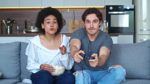 Excited Couple Playing Video Games with Popcorn