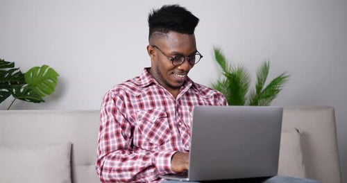 Excited Young Adult Using Laptop on Couch