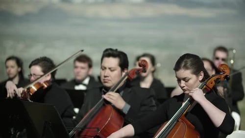 Shot of outdoor orchestra, close up on the musicians playing string instruments