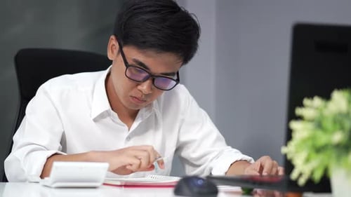 young man studying and using calculator
