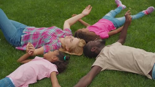 United Family Holding Hands Lying on Lawn in Circle
