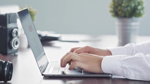 Hands Typing on Laptop at Photographer's Desk