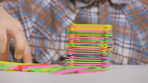 Niño construye una pirámide de palos de colores