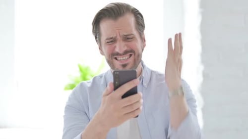 Man Reacts in Disbelief at Something on Phone