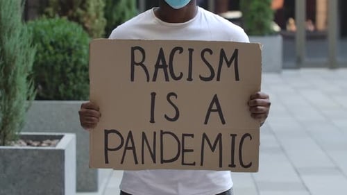Protester Holds a Sign on Urban Sidewalk
