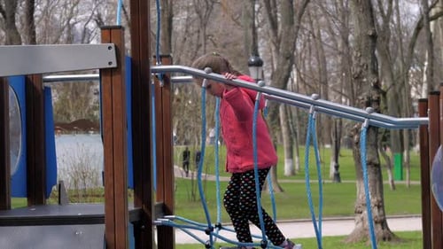 Junior Schoolgirl Walks Along Suspension Bridge in Park