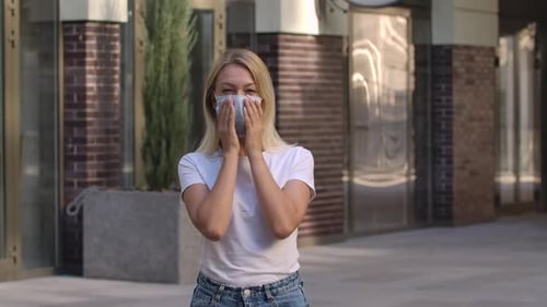 Woman Puts on Protective Face Mask Outside