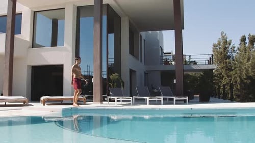 Young Traveler taucht in den Pool ein und spritzt Wasser
