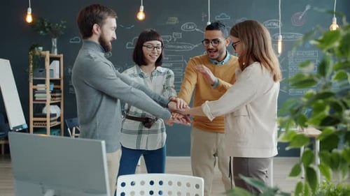 Multi-ethnic Business Team Joining Hands in Office Expressing Cooperation Then Laughing