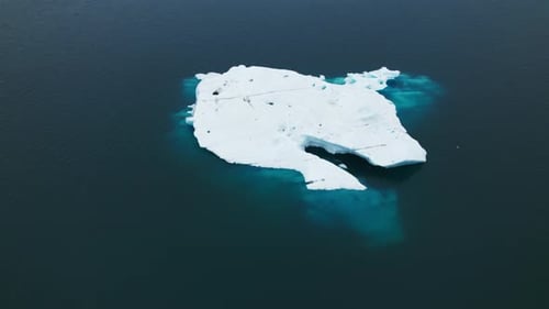 Magnificent Aerial Shot of an Iceberg Floating in Blue Ocean Water Iceland