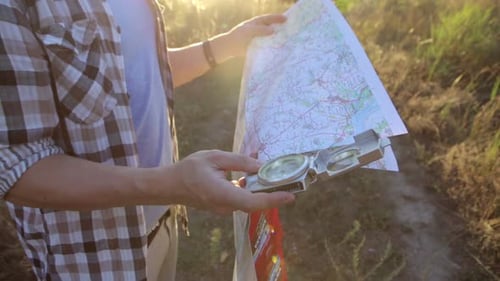 A man with a map and a compass in his hands is looking for a way