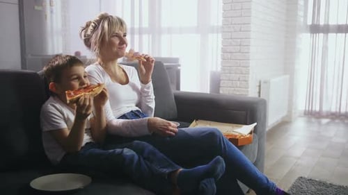 Mother and Child Enjoy Pizza Together on Sofa