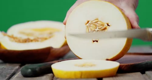 Mains mâles tranchant un melon mûr en tranches rondes.