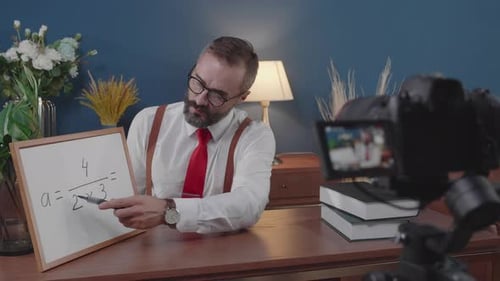 Bearded Man Explains Math Problem at Desk