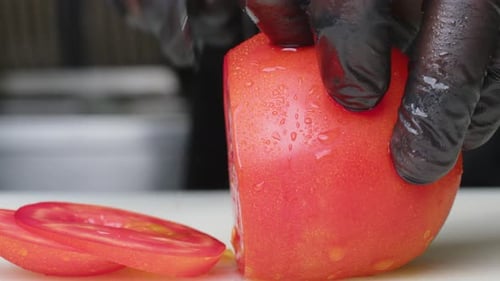 Chef Takes Cherry Tomatoes Cuts Vegetable Into Halves with Kitchen Knife on Dark Cutting Board
