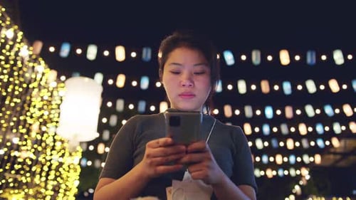 Woman Uses Phone, Puts on Face Mask at Night