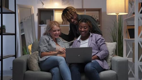 Friends Gathered Around Laptop on Couch