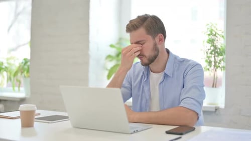 Young Adult Experiencing Headache While Working on Laptop