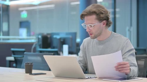 Young Adult Works Diligently at Laptop in Office