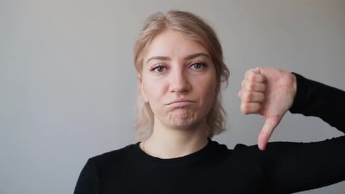 Woman Gestures Thumbs Down, Expressing Disapproval