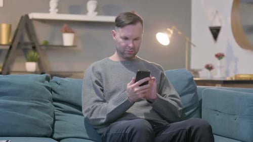 Man Using Smartphone on Couch at Home