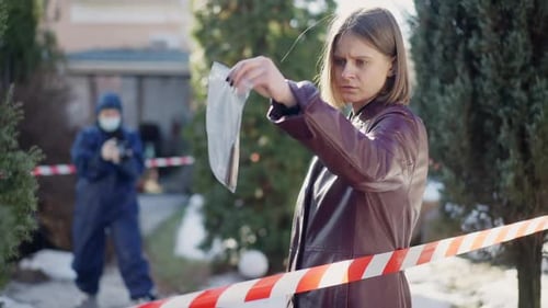 Woman Holds Evidence Bag at Crime Scene
