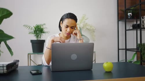 Schöne junge brünette Geschäftsfrau, die am Laptop arbeitet und im bequemen Stuhl sitzt