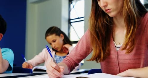 Students Writing at Desks in Classroom