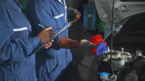 Mechanic man and woman in uniform checking diagnostic for fix and repair car together at garage.