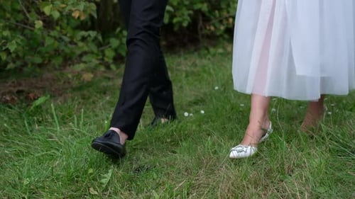 Walking Young Couple in the Park Feet on the Grass