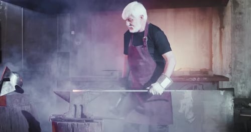 Senior Blacksmith forging Metal in Workshop