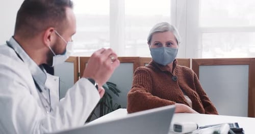 Doctor Discussing Treatment with Senior Woman in Clinic