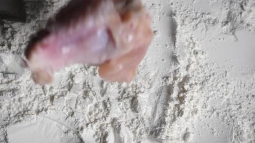 Chef puts the chicken into the flour tray